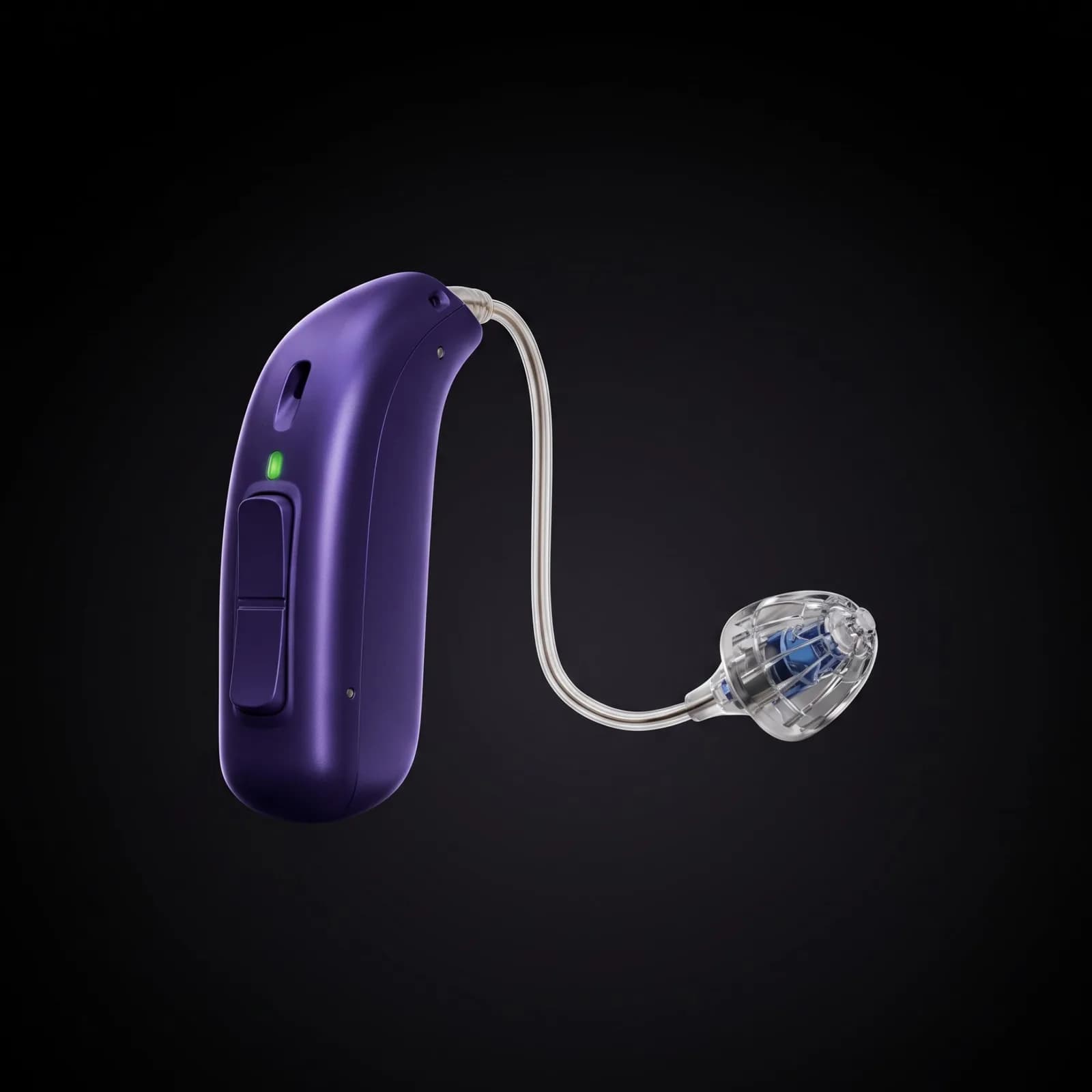 A tiny modern hearing aid with a transparent earpiece photographed in studio light